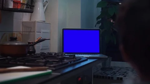 Guy watching at chroma key notebook computer display at kitchen near stove Stock Footage 83253149