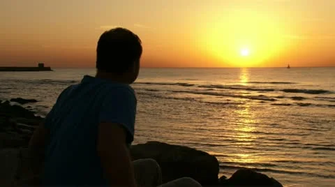 Guy watching sunset at the beach Vídeo Stock 20512924