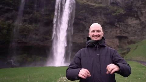 Guy on a waterfall shows a heart with his hands Stock Footage 256890767