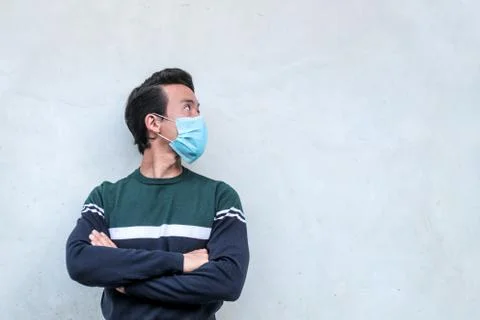 Guy wearing a face mask, standing in front of a white wall Stock Photos
