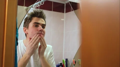 The guy wears aftershave balm on his skin, skin care Stock Footage 264888057