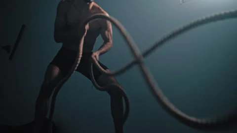 Guy whips ropes in wave motion at gym Stock Footage 275436863