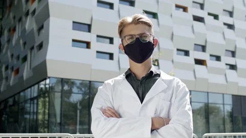 Guy In White Coat Stands On The Background Of Tall Building. Young Guy With 스톡 동영상 143415544