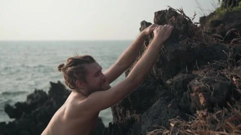 A guy of white color with a bare torso, climbs the rock. Stock Footage 234020677