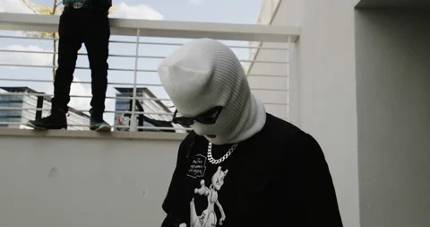 Guy in a white ski mask, chain and sunglasses acting tough with guy in the Stock Footage 231189849
