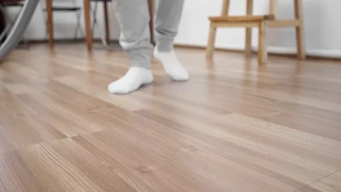 A guy in white socks cleans the floor with laminate with a vacuum cleaner. Stock Footage 149755025
