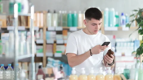 Guy in a white t-shirt scans the barcode of medicated syrup for cough and cold Stock Footage 312231424