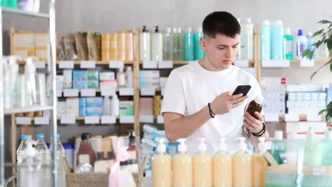 Guy in a white t-shirt scans the barcode of medicated syrup for cough and cold Stock Footage 323068643
