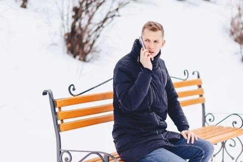 The guy in the winter jacket speaks on the phone on the street Stock Photos