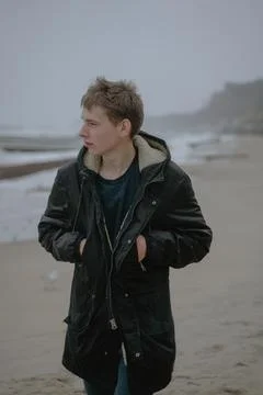 A guy in a winter jacket walks along the beach, grinds to the side, a teenage 写真素材