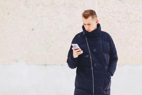 Guy in winter jacket writes sms Stock Photos