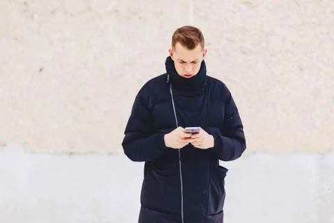 Guy in winter jacket writes sms Foto stock