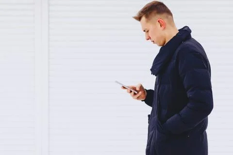 Guy in winter jacket writes sms Foto stock