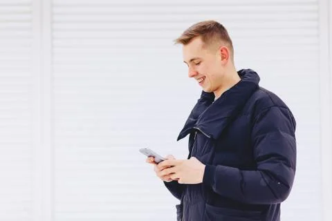 Guy in winter jacket writes sms Stock Photos