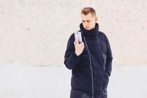 Guy in winter jacket writes sms Foto stock