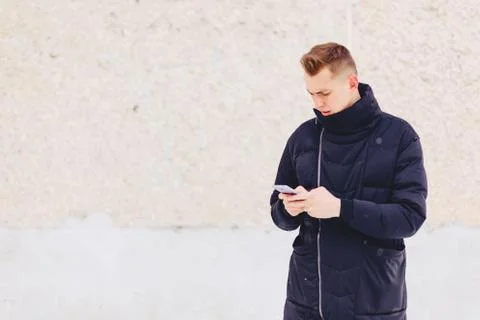 Guy in winter jacket writes sms Stock Photos