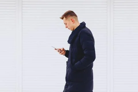 Guy in winter jacket writes sms Stock Photos