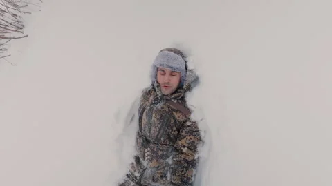 A guy in winter joyfully falls into the snow with his back. Stock Footage 327716979