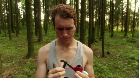 A guy in the woods is looking at a different smoking devices. Stock Footage 197481426