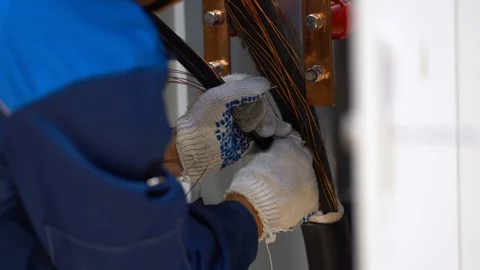 Guy working inside electric switchboard, mount thick three-wire cable Stock Footage 126357929