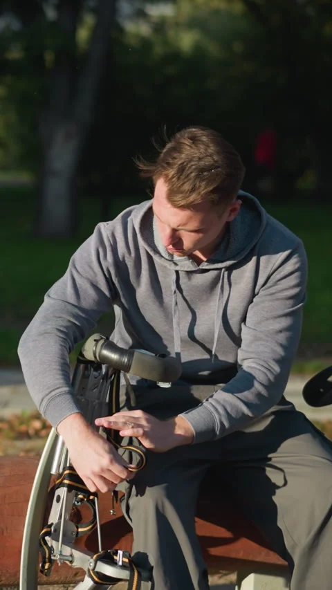 Guy Working on Modified Mobility Device Outdoors in Sunny Park Setting Stock Footage 310200689