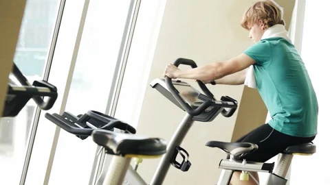 A guy working out on the exercise bike in the morning in the gym. Active sport h Stock-Footage 99072009