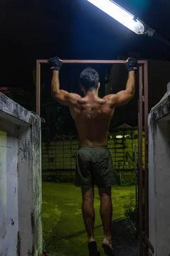 Guy working out in the street, doing pull-up, with neon lights. Stock Photos
