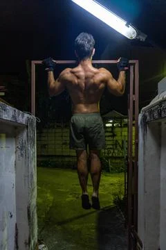 Guy working out in the street, doing pull-up, with neon lights. Stock Photos