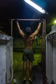 Guy working out in the street, doing pull-up, with neon lights. Foto stock