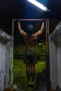 Guy working out in the street, doing pull-up, with neon lights. Stock Photos