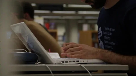 A guy works on a white computer in college library Stock Footage 36174183