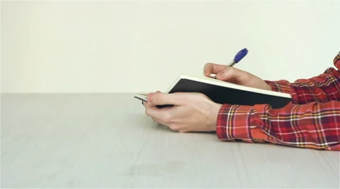 A guy writes notes in a notebook with a pen on a table Video stock 45440727
