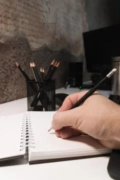 The guy writes with a pencil in a notebook Stock Photos