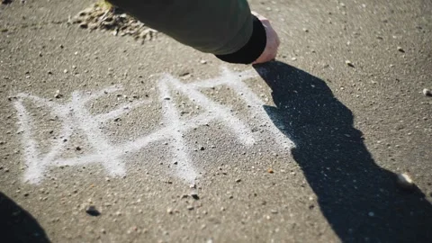 The guy writes the word "DEATH" on the asphalt in white chalk. Close up Stock Footage 130464872