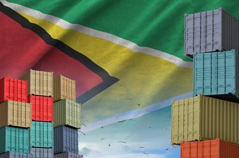 Guyana flag and big stack of shipping cargo containers in docks with sky Stock Photos