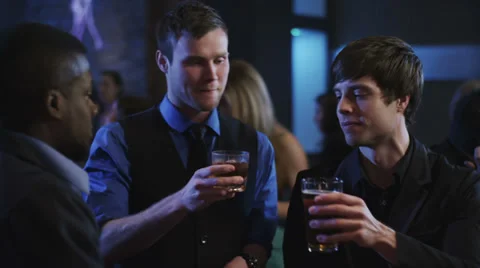 Guys cheering their drinks at a bar and  a guy getting his hair messed Stock Footage 34005417