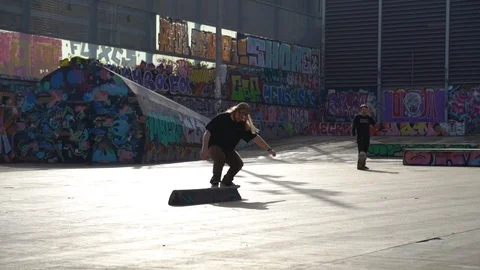 The guys does tricks on a skateboard in a skate park painted with graffiti Stock Footage 101269281