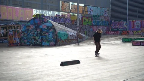 The guys does tricks on a skateboard in a skate park painted with graffiti Stock Footage 101269307