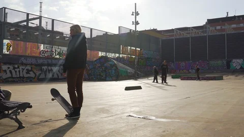 The guys does tricks on a skateboard in a skate park painted with graffiti Stock Footage 101269314