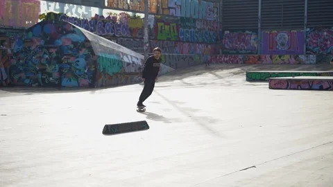 The guys does tricks on a skateboard in a skate park painted with graffiti Stock Footage 101269336