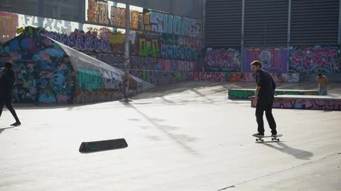 The guys does tricks on a skateboard in a skate park painted with graffiti Stock Footage 101269518