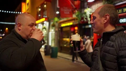 Guys drinking a beer in the Temple Bar district of Dublin by night - travel Video stock 229443850