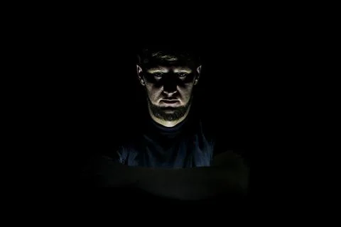The guy's face on a dark background, with an isolated light. Stock Photos