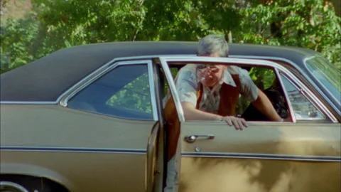 A guys gets out of  a  car to pick up his hat Stock Footage 272284319