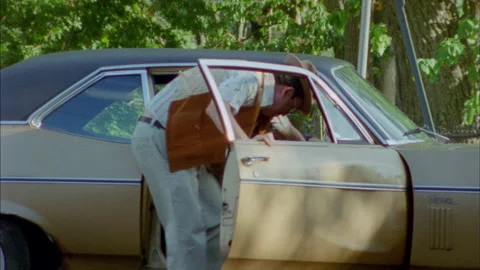 A guys gets out of a car to pick up his hat Stock Footage 272285613