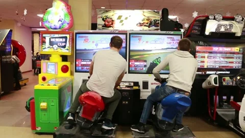 Guys play motorcycle racing on a computer simulator Stock Footage 135191367