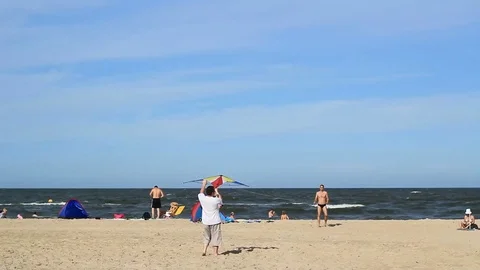 Guys practicing with a kite on a beach Stock Footage 99119115