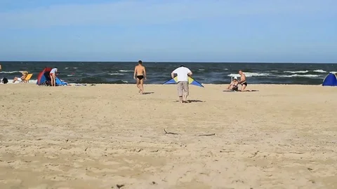 Guys practicing with a kite on a beach Stock Footage 99119126