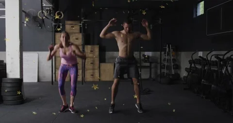 Gym duo doing burpees, pressing up then jumping, gold star confetti overlay Video stock 328265599