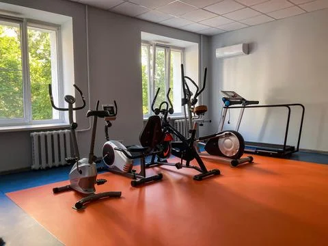 A gym interior with exercise machines on a blue mat, contrasting light gray.. Stock Photos